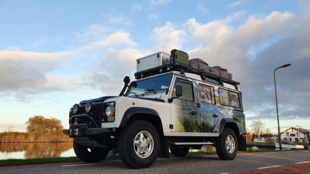 land rover defender at the water with roofrack and survival gear